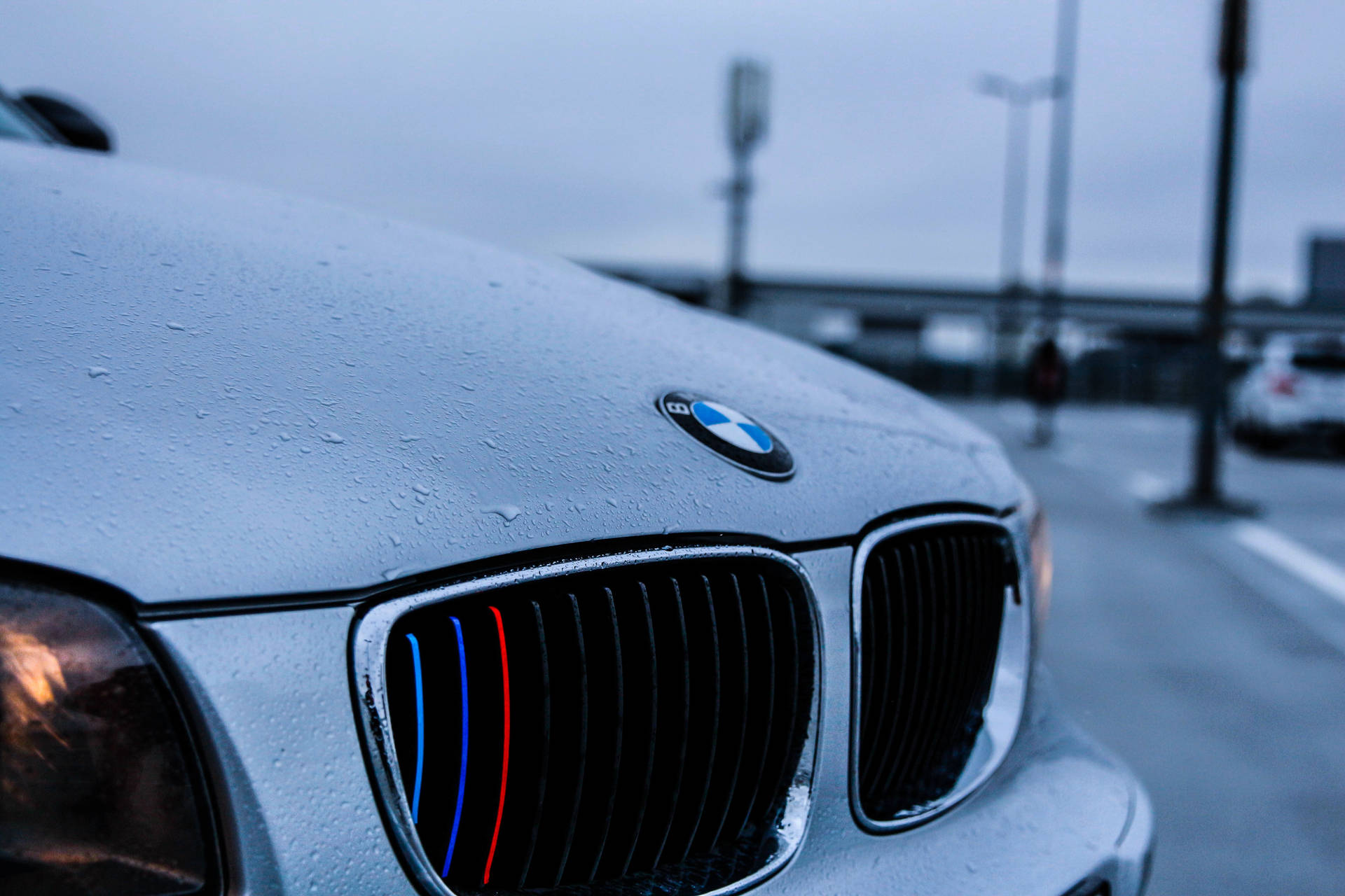 Lähikuva valkoisen BMW-auton konepellistä sadepisaroiden kanssa -taustakuva