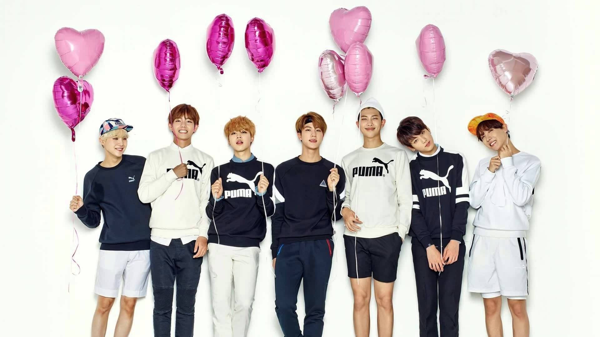 BTS hymyilee ja pitää sydänilmapalloa taustakuva