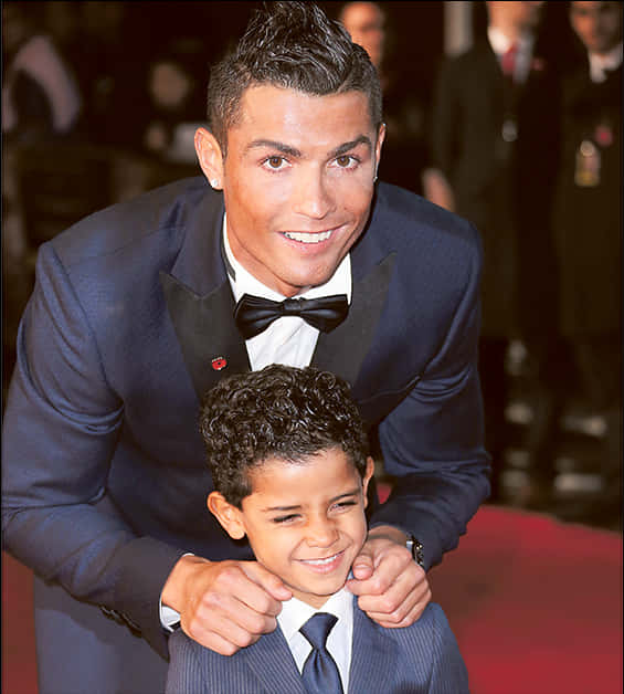 Cristiano Ronaldo hymyilevä lapsen kanssa tapahtumassa Taustakuvat
