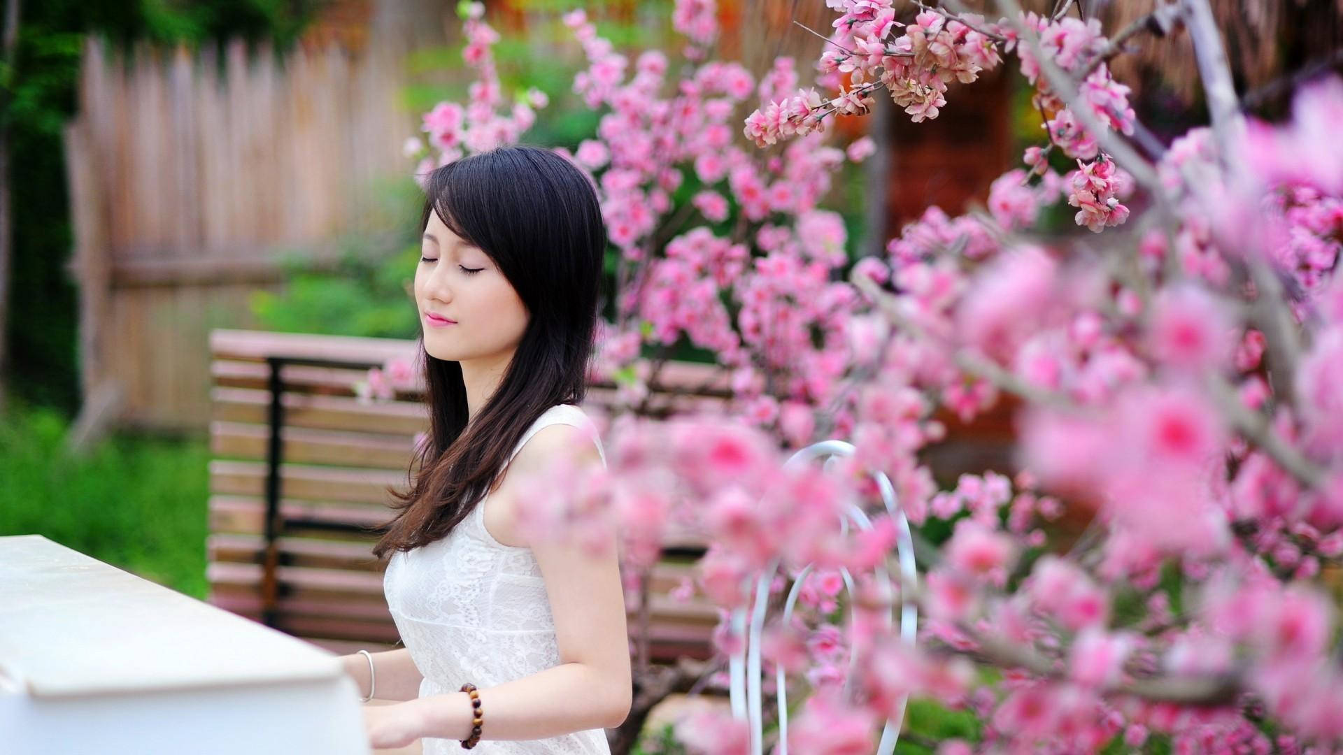 Japanilainen tyttö soittaa pianoa vaaleanpunaisessa kukkatarhassa Taustakuvat
