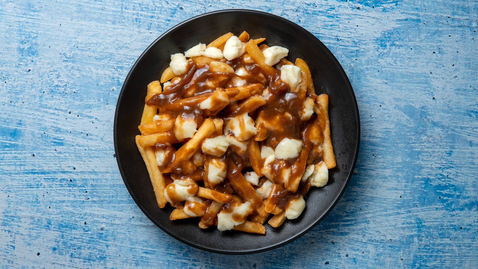 Maukas lautasellinen kanadalaista poutinea Taustakuvat