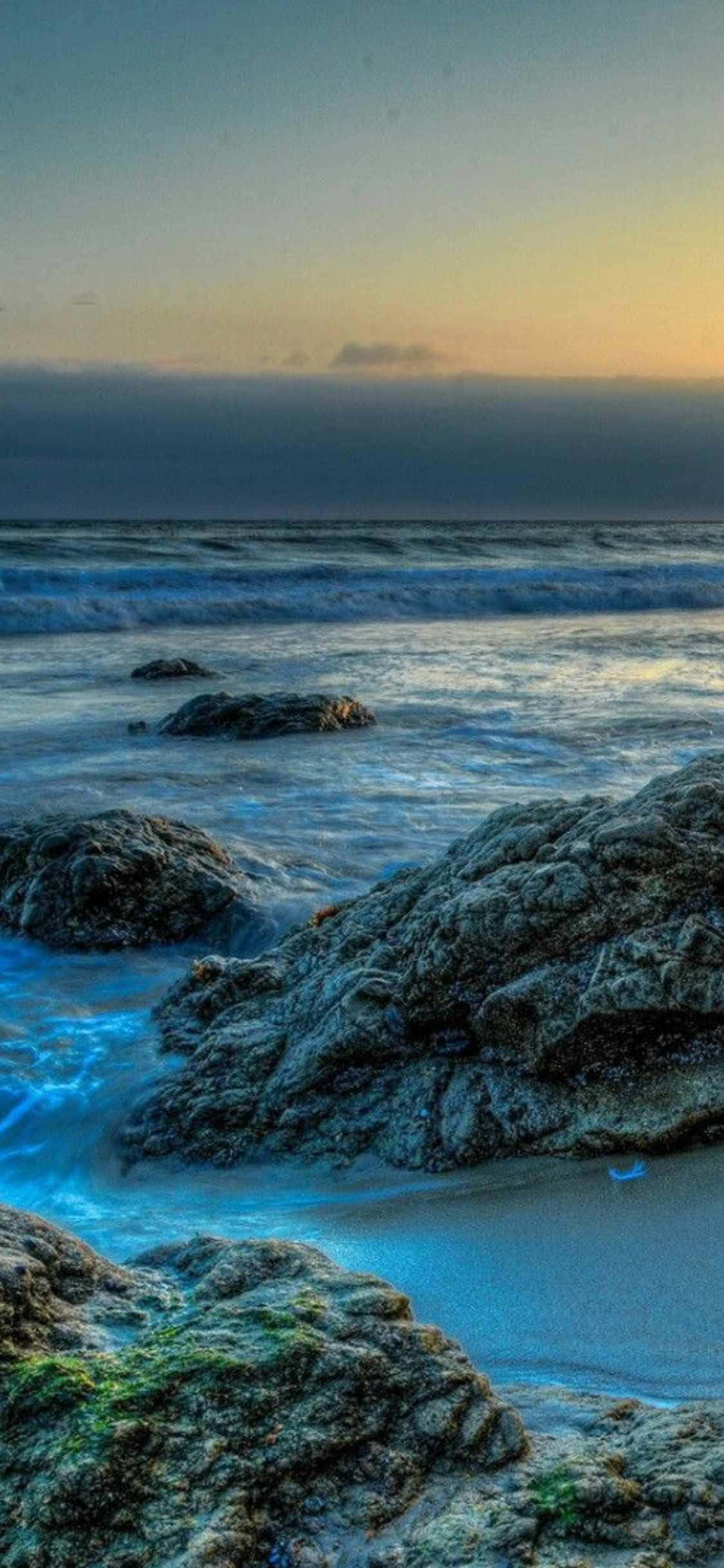 ranta kivillä ja vedellä auringonlaskussa Taustakuvat