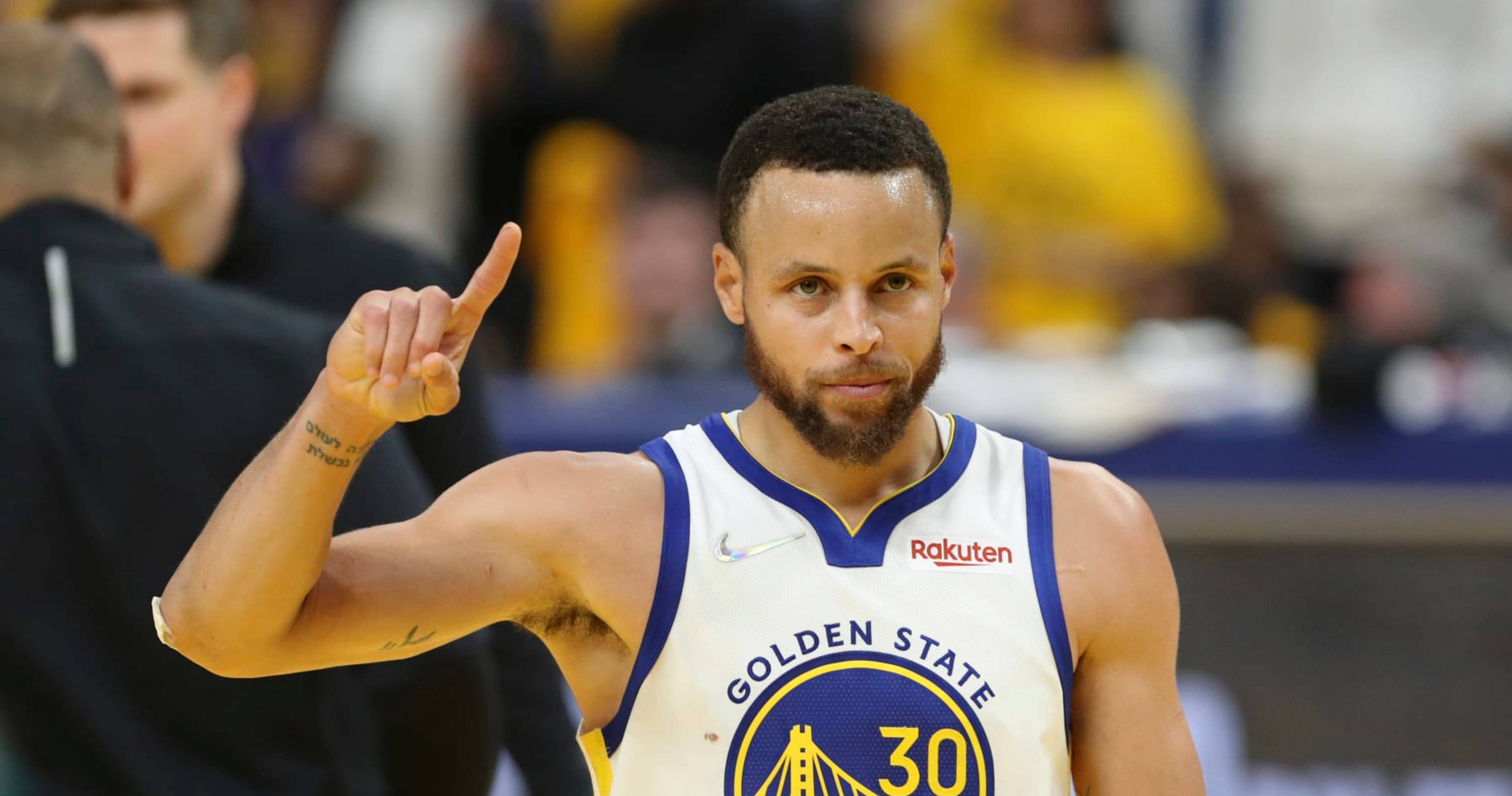 Steph Curry osoittaa oikealla kädellä ylös Taustakuvat