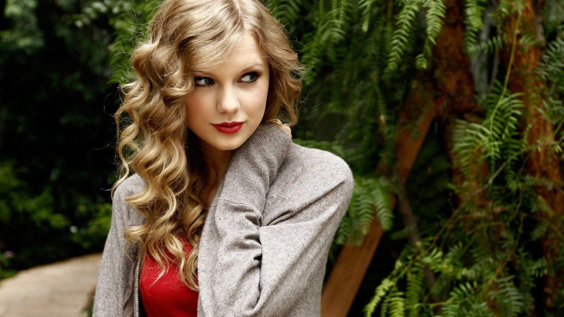Söpö kihara Taylor Swift sivukatseposeeraus -taustakuvavalokuva