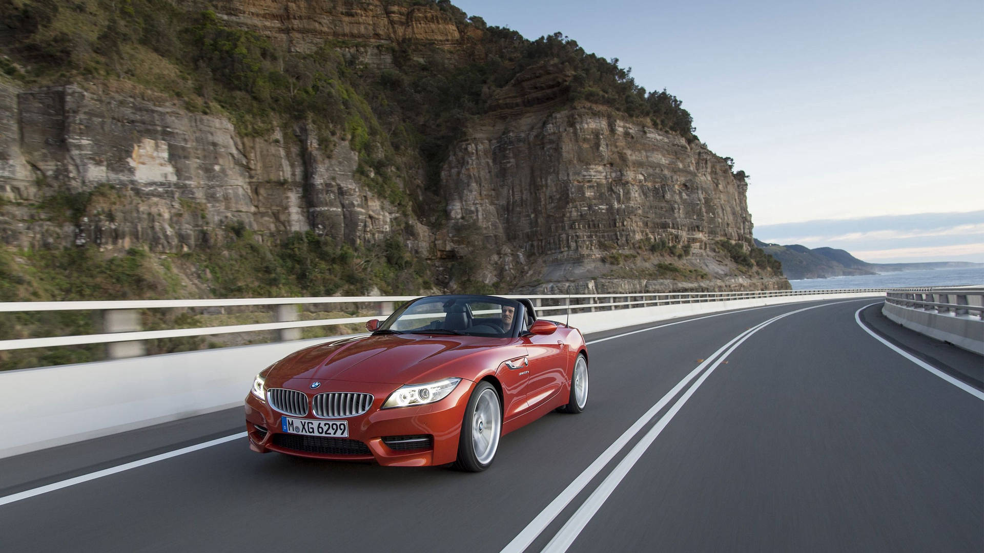 Oranssi BMW Z4 -auto tiellä vuoren vieressä -taustakuva
