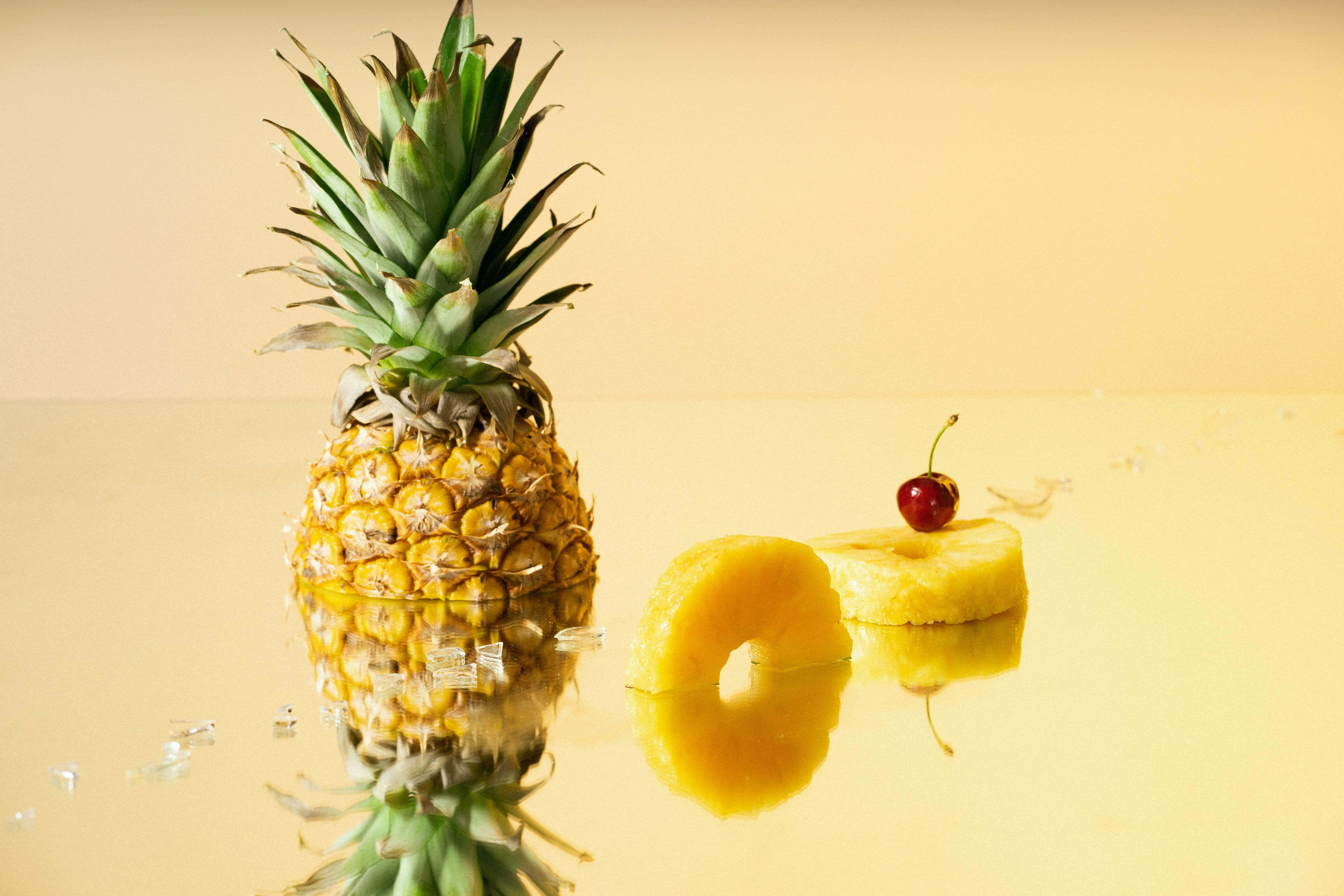 Tuore ja mehukas ananas seisoo maalauksellisen auringonlaskun etualalla. Taustakuvat