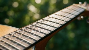 Lähikuva kitaran kielistä vihreällä bokeh-efektillä ja lämpimässä auringonvalossa. — Musiikkia estetiikka Taustakuvat