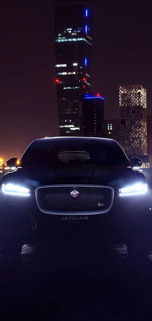 Mustan Jaguar-auton taustakuva yöllä etuvalot päällä