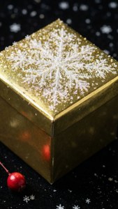 Kiiltävä kultainen lahja lumihiutaleiden kanssa mustalla pinnalla marjan kera. — iPhone 7 Taustakuvat