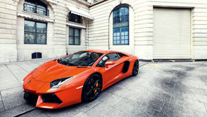 Oranssi Lamborghini Aventador rakennustaustakuvalla.