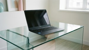 Puhdas minimalistinen kohtaus, jossa Chromebook on lasipöydällä.
