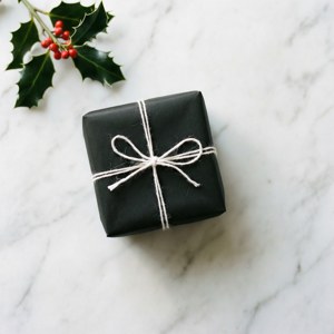 Yksinkertainen mustavalkoinen paketti hollyn kanssa marmoripinnalla. — Joululahjat Taustakuvat