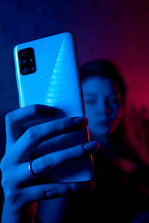Nainen puhelimen kanssa neoninsinisessä iPhonessa — Xiaomi Pad 9 Pro Max Taustakuvat
