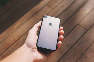 henkilö pitää kiiltävän mustaa iPhone 7:ää