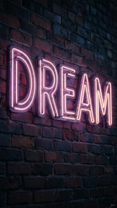 Neonkyltti 'DREAM' tiiliseinällä yöllä, tunnelmallinen ja taiteellinen. — iPad Taustakuvat